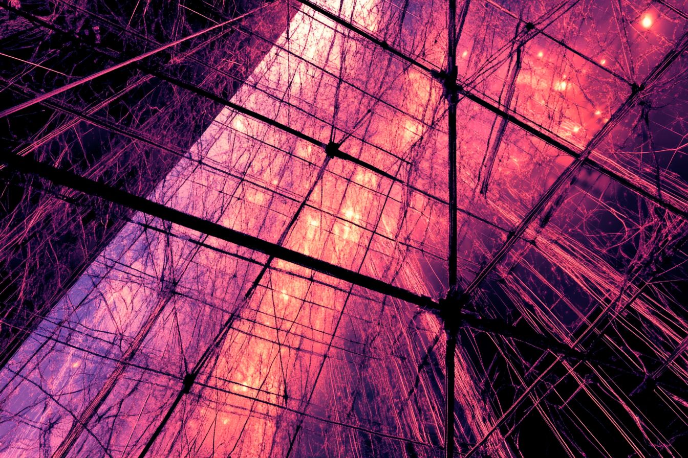 An abstract metal cage with intricate geometric patterns, faintly illuminated in purple and pink, suspended in a dark void.